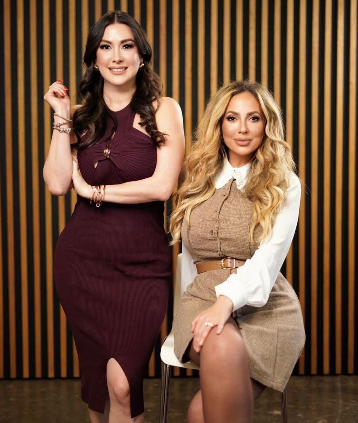 The two founders of Monarch & Co. posed in front of a wood-slat wall, one standing and one seated